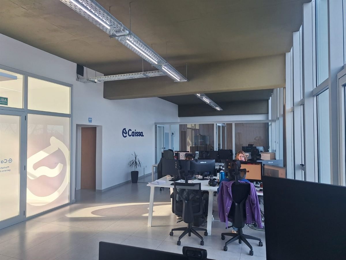 Interior de la oficina de Caissa en Neuquén Capital: espacio de trabajo con el equipo y el logo de la agencia en la pared